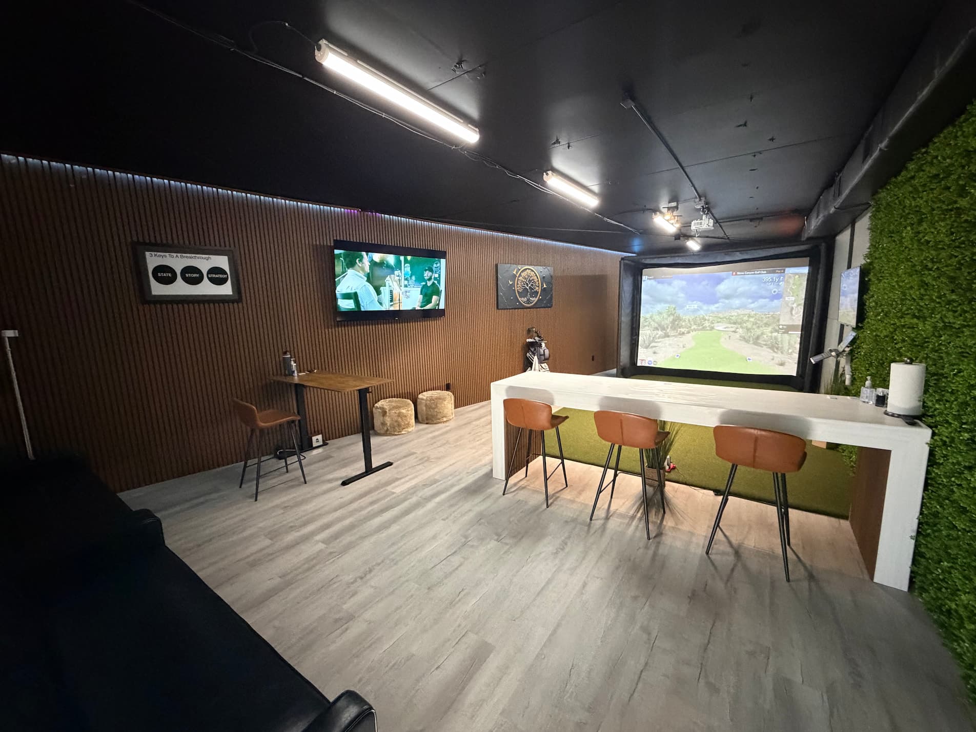 Private golf simulator lounge interior with TV, dartboard, comfortable seating and modern decor at Golf Lounge Satellite Beach FL